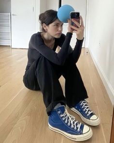 a woman sitting on the floor holding up a blue frisbee in front of her face