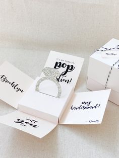 three white boxes with wedding rings on them and some cards that say pop up when they're married