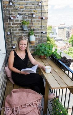 a woman sitting on a bench reading a book and holding a coffee cup in her hand