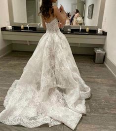 a woman in a wedding dress is taking a selfie with her cell phone while looking at herself in the mirror