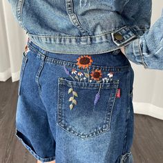 the back of a woman's jean shorts with embroidered flowers on it and an orange sunflower