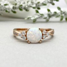 a white opal and diamond ring sitting on top of a table