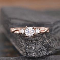 a three stone diamond ring sitting on top of a rock