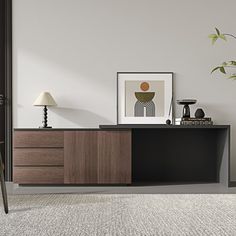 an empty living room with a plant on the sideboard and pictures hanging on the wall