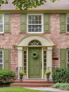 a brick house with green shutters and a wreath on the front door