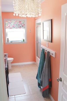 a bathroom with pink walls and white tile flooring, chandelier above the sink