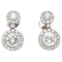 These drop earrings showcase a captivating duo of round diamonds, each boasting 1.51 and 1.50 carats. Graded H for near-colorless beauty and VS2 clarity, they sparkle with exceptional brilliance. Their elegance is further amplified by a sparkling halo, meticulously set with 50 round diamonds. Prong settings securely hold these precious stones, while the 18k white gold frame offers a touch of luxury. Butterfly backs closure ensure a comfortable and secure fit. Details:  ✔ Item Type: Drop Earrings ✔ Metal: 18k White Gold ✔ Weight: 4.98 grams ✔ Setting: Prong, Halo ✔ Closure: Butterfly back Stone Details (1): ✔ Gemstone: 2 Diamonds ✔ Carat: 1.51, 1.50 ✔ Color: H ✔ Cut: Round ✔Clarity: VS2 ✔ Measurements: 7.46 x 7.52 x 4.53 mm ✔ GIA Certificate #: 5161509015 Side Stone Diamonds: ✔ 2 round diam Gia Certificate, Halo Setting, Fit Details, Diamond Drops, 3 Carat, Diamond Drop Earrings, Gold Frame, Prong Setting, Precious Stones