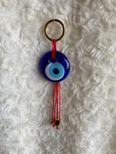 a blue evil eye keychain hanging on a white furnishing with beads