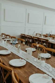 the table is set with white plates and place settings for guests to sit down at