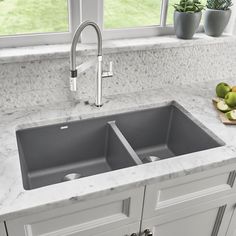 a kitchen sink sitting under a window next to a counter top with fruit on it