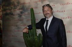 a man in a suit and tie standing next to a large cactus with the caption salvation salvation written on it