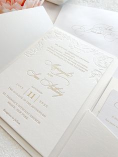 the wedding stationery is laid out on top of each other, with flowers in the background