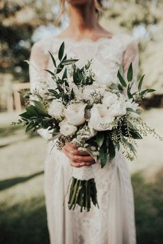 a woman holding a bouquet of white flowers