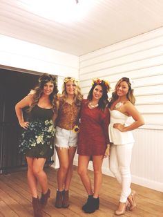 four beautiful women standing next to each other in front of a white wall and wooden floor