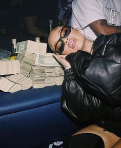 a woman in sunglasses is laying on a couch covered with stacks of cash and money