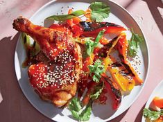 a white plate topped with chicken and veggies on top of a pink table