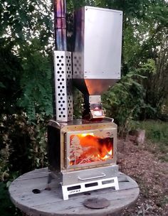 a stove that is sitting on top of a wooden table in the woods with flames coming out of it