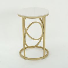 a white and gold side table with an oval design on the top, against a plain background