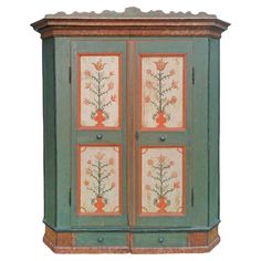 an old green cabinet with flowers painted on the front and side panels, sitting against a white background