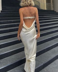 a woman in a white dress walking down some steps with her back to the camera