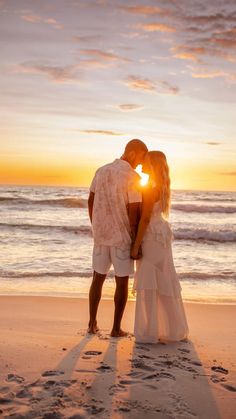 a couple kissing on the beach at sunset