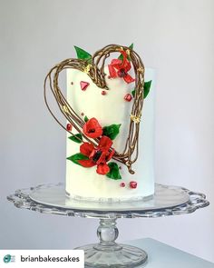 a heart shaped cake decorated with flowers and vines on a clear plate, against a white background