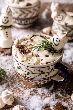 two mugs filled with hot chocolate and marshmallows on top of snow covered ground