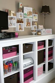 a white shelf filled with lots of pink and brown bins next to a flat screen tv