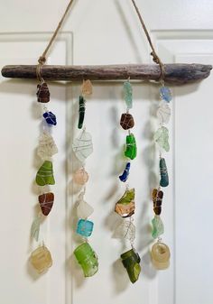 a piece of driftwood hanging from a door with sea glass beads and seashells