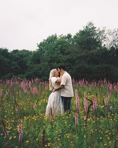 a man and woman kissing in a field full of wildflowers