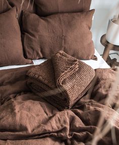 a bed covered in brown linens and pillows with a blanket on top of it