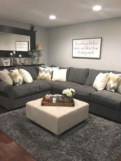 a living room with gray couches and white pillows on the rugs in front of it