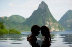 two people in the water facing each other with mountains in the backgrouds