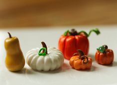 miniature pumpkins and peppers on a white surface