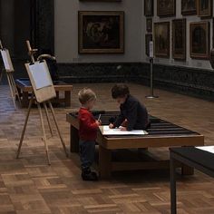 two young boys playing with an easel in a museum