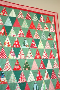 a quilted christmas tree wall hanging in a room with red and green trimmings