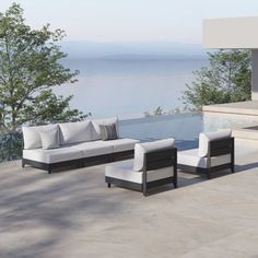 an outdoor living area with couches, tables and water view in the background on a sunny day