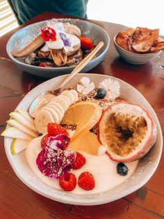 a plate full of fruit and yogurt on a table with other food items