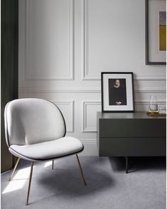 a white chair sitting next to a dresser in a room with wall art on the walls