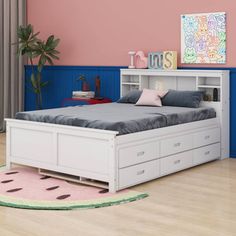 a white bed with drawers underneath it in a pink and blue walled room, next to a potted plant