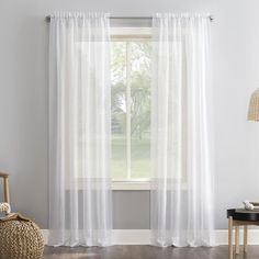 a living room with white curtains and a wicker chair