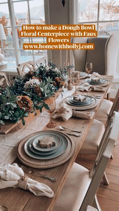 a dining room table set with place settings and flowers on the centerpiece, in front of large windows