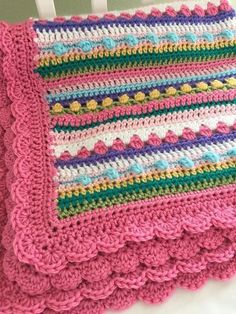 a pink crocheted blanket sitting on top of a white chair