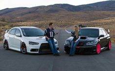 two people are sitting on the hood of their cars and one is pointing at something