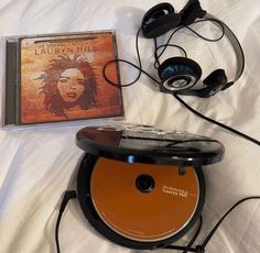 there is a cd and headphones on top of the bed with an orange case