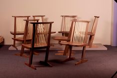 three wooden chairs sitting next to each other on top of a carpeted floor in front of a wall