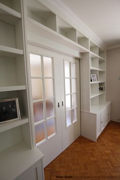 an empty room with white bookcases and wooden floors