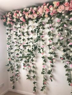 the wall is covered with pink and white flowers, hanging from it's sides