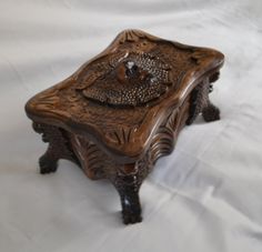 an ornate wooden box on a white sheet covered tablecloth, with the lid open