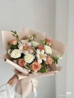 a woman holding a bouquet of white and pink flowers in her hand with a ribbon tied around it